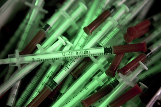 Insulin syringes on multicolored background out of focus