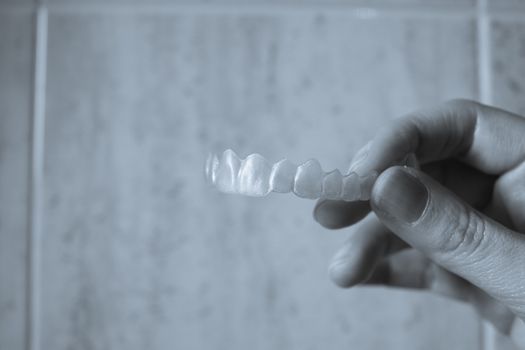 Hand of woman holding invisible dental retainer