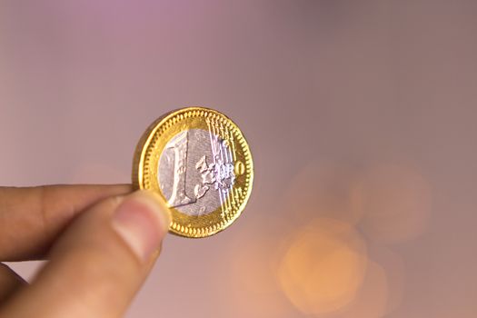 Chocolate euro between the fingers of a woman