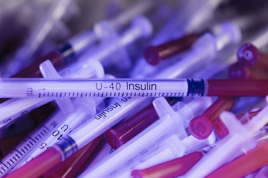 Insulin syringes on multicolored background out of focus