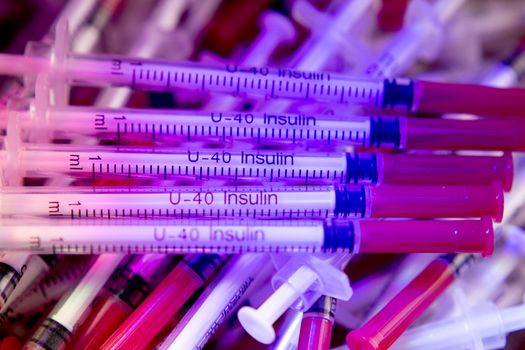 Insulin syringes on multicolored background out of focus
