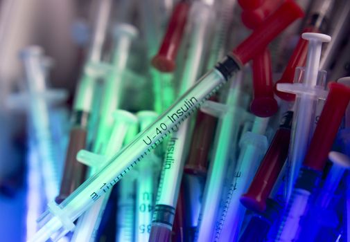 Insulin syringes on multicolored background out of focus