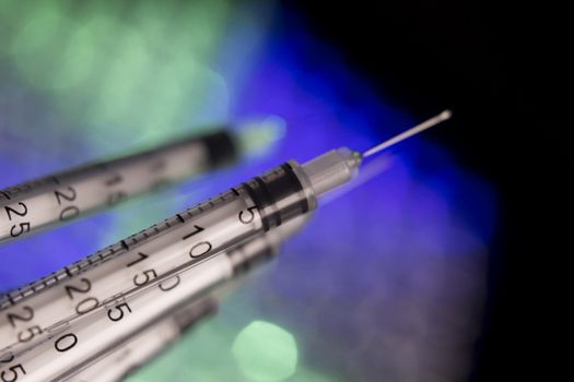 Insulin syringes on multicolored background out of focus