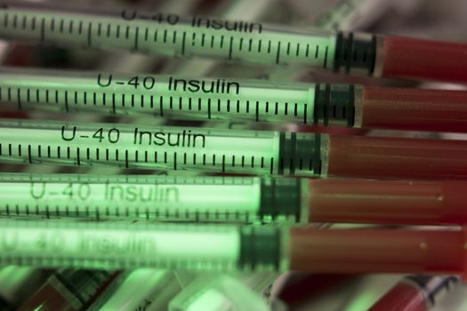 Insulin syringes on multicolored background out of focus