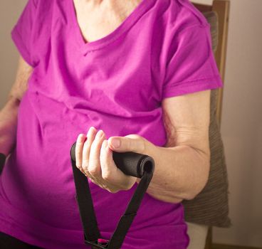 Rehabilitation exercises with elastic resistance rubber for older woman with cerebral stroke