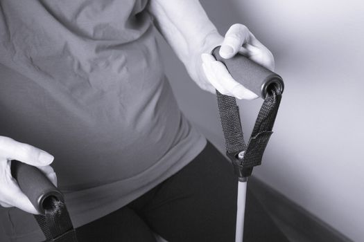 Rehabilitation exercises with elastic resistance rubber for older woman with cerebral stroke