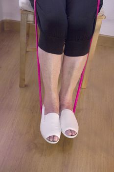 Rehabilitation exercises with elastic resistance rubber for older woman with cerebral stroke