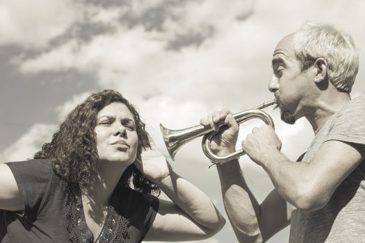 Man and woman playing trumpet on sky background