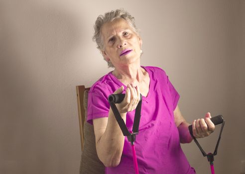Rehabilitation exercises with elastic resistance rubber for older woman with cerebral stroke