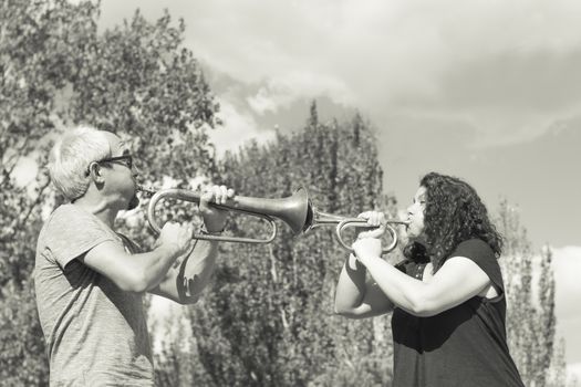 Man and woman playing trumpet on sky background