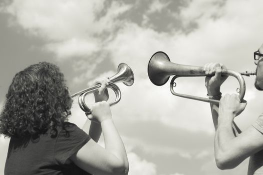 Man and woman playing trumpet on sky background