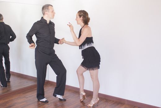 Couple of dancers with attractive latin costumes dancing salsa and different latin caribbean rhythms
