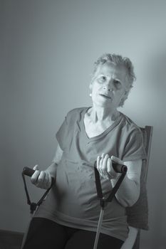 Rehabilitation exercises with elastic resistance rubber for older woman with cerebral stroke