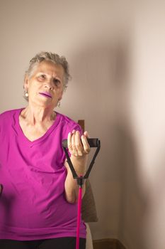Rehabilitation exercises with elastic resistance rubber for older woman with cerebral stroke