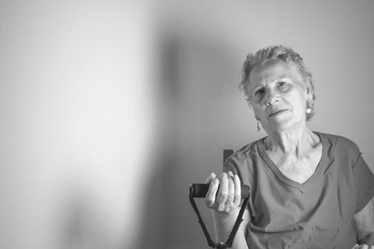 Rehabilitation exercises with elastic resistance rubber for older woman with cerebral stroke