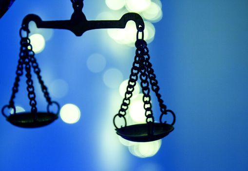 Scales of justice on bright lights background