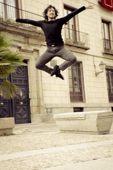 Male dancer performing jump in the air. Urban background