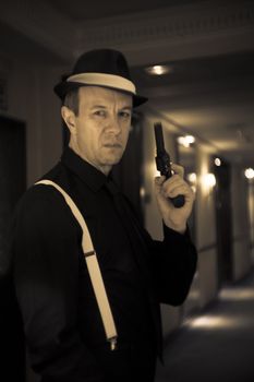 Ganster with gun in situation of alert and danger. Costume with hat.