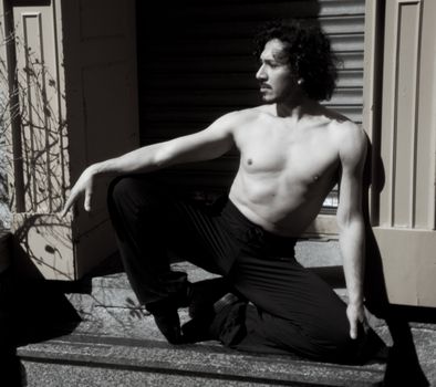 Latin male dancer posing with dancing figures. Urban background