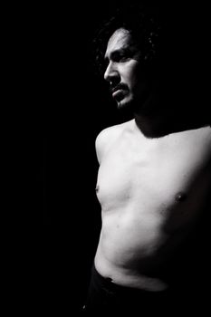 Portrait of latin man with beard and curly black hair. Naked torso