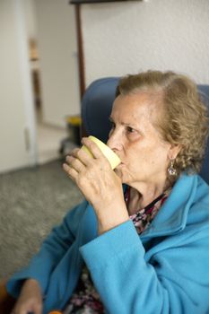 Older woman drinking water from a glass to hydrate