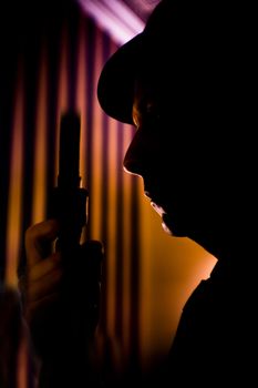 Ganster with gun in situation of alert and danger. Costume with hat.