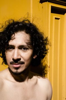 Portrait of latin man with beard and curly black hair. Naked torso