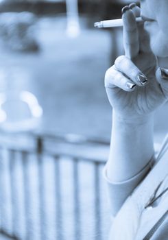 Womans hand holding a cigarette while smoking