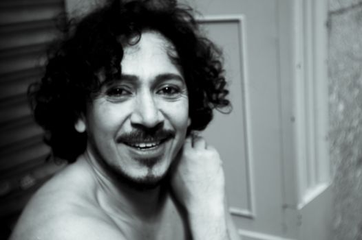 Portrait of latin man with beard and curly black hair. Naked torso
