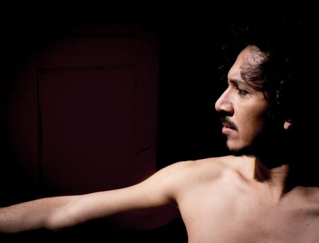 Latin male dancer posing with dancing figures. Urban background