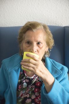 Older woman drinking water from a glass to hydrate