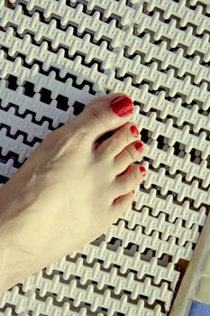 Bare feet of woman with nails painted red. Pool background