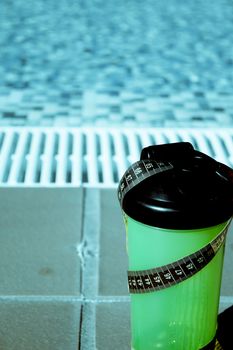 Shake mix bottle surrounded by a measuring tape on the edge of a summer pool