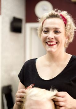 Hairdresser in positive attitude brushing the hair of a client