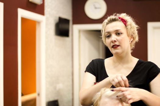 Hairdresser in positive attitude brushing the hair of a client