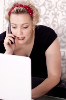 Woman talking on the phone with a computer to take an appointment