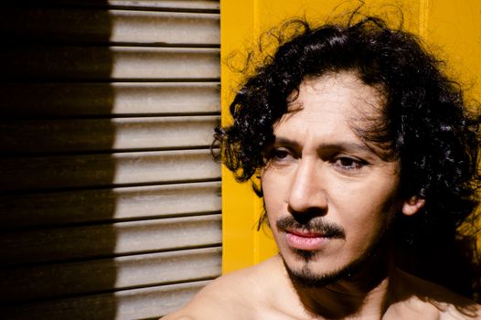 Portrait of latin man with beard and curly black hair. Naked torso