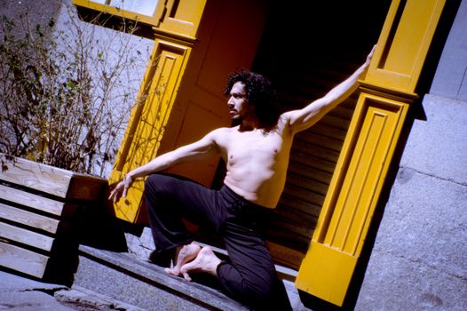 Latin male dancer posing with dancing figures. Urban background