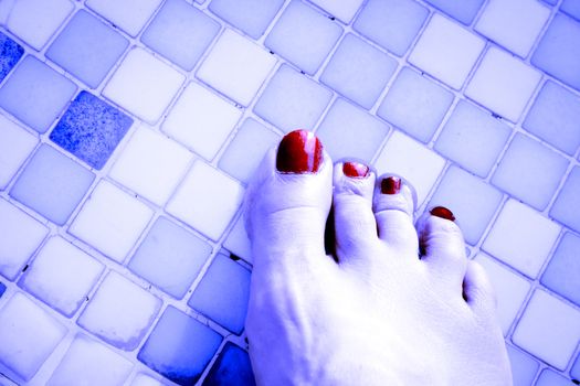 Bare feet of woman with nails painted red. Pool background