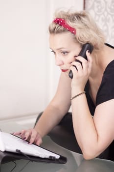Woman talking on the phone with a computer to take an appointment