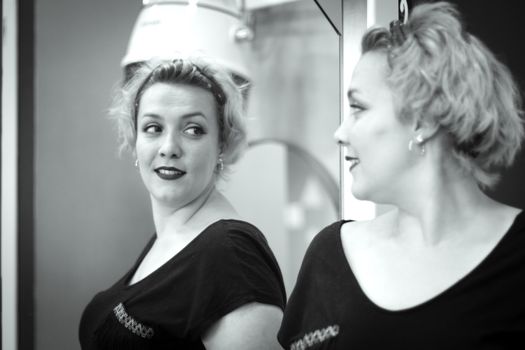 Blonde woman looking in the mirror of a hairdresser. Professional concept