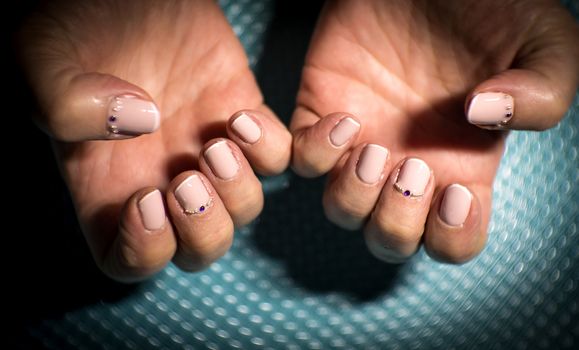 Womans hands showing semi-permanent beige manicure