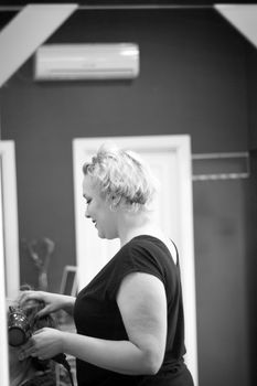 Hairdresser drying hair with red hand dryer