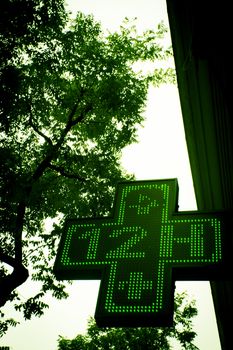 Pharmacy sign indicating open twelve hours. Green cross