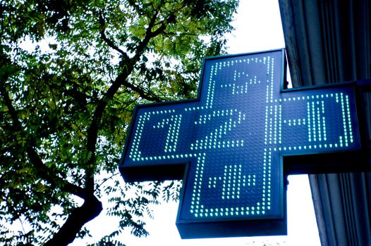 Pharmacy sign indicating open twelve hours. Green cross