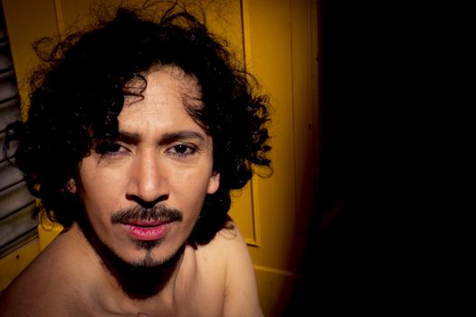 Portrait of latin man with beard and curly black hair. Naked torso