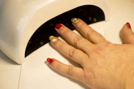 Womans hand drying nails with uv led lamp