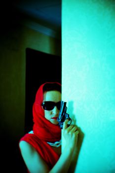 Woman dressed in red with dark glasses and gun in her hand