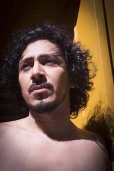 Portrait of latin man with beard and curly black hair. Naked torso