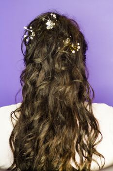Woman with curly black hair and long ornate with hairpins on white